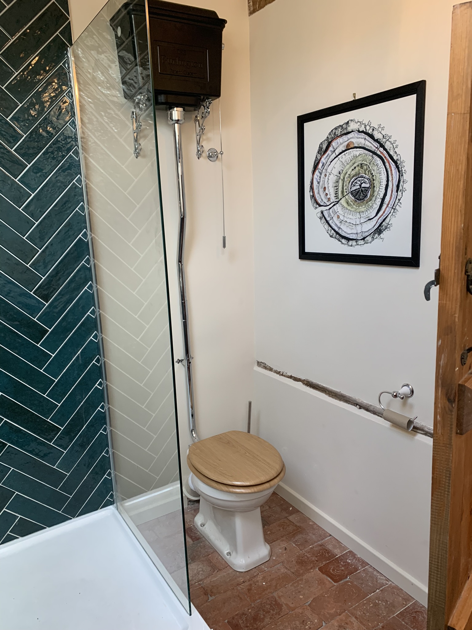 Bathroom with a teal herringbone shower, high-level cistern and terracotta floor