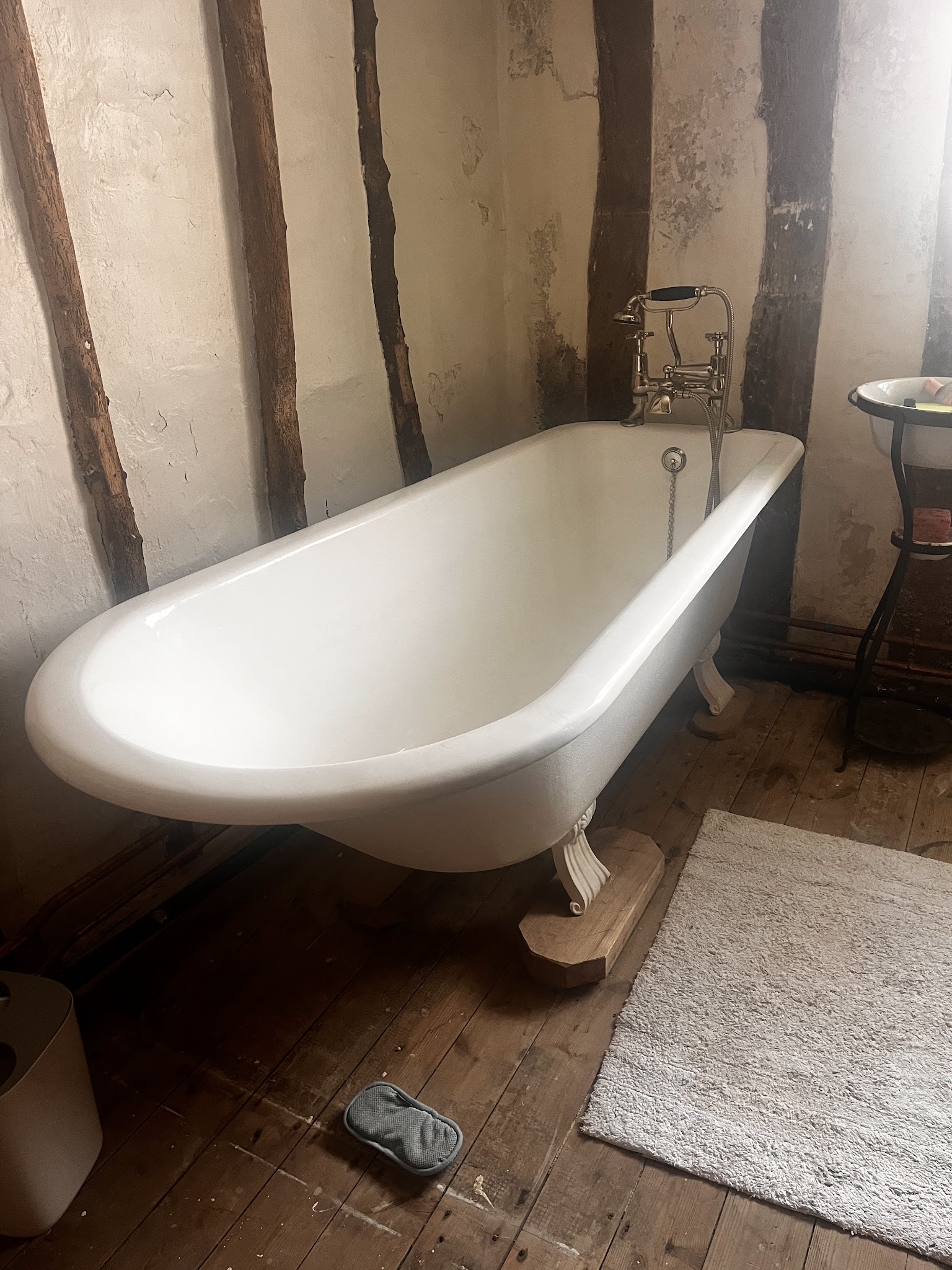 White cast-iron roll-top bath on claw feet in a timber-framed bathroom